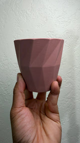 Pink faceted ceramic cactus pot held in a hand to show its size